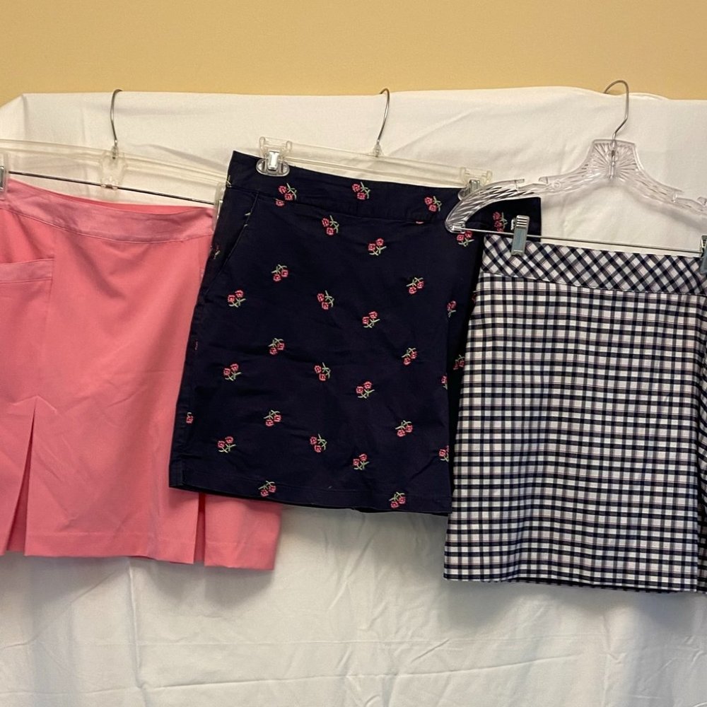 Three golf skorts.  Two Izod (blue and plaid) one EP (pink).